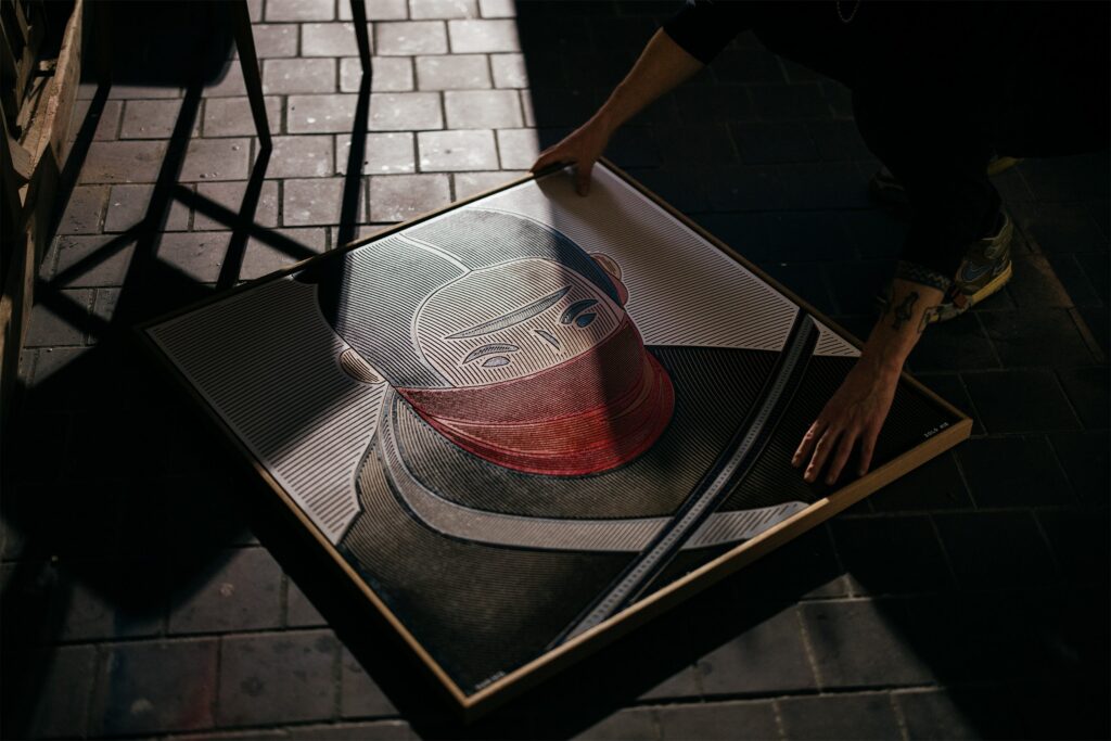 Hariko by Zolo Kis — the framed warrior portrait resting on chairs in sunlight