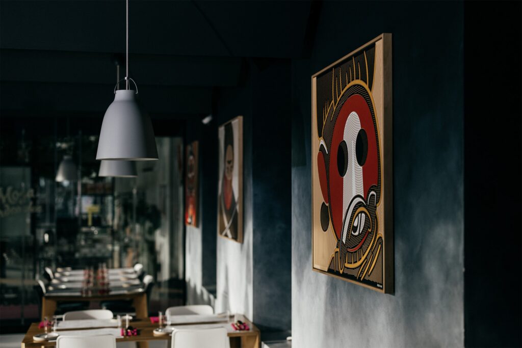 Tukumora by Zolo Kis — the warrior portrait displayed inside a restaurant beside pendant lights
