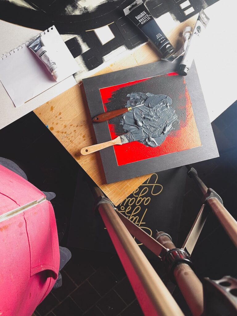Backstabbed Boy by Zolo Kis — painting in progress on a worktable with masking tape, tools and red paint