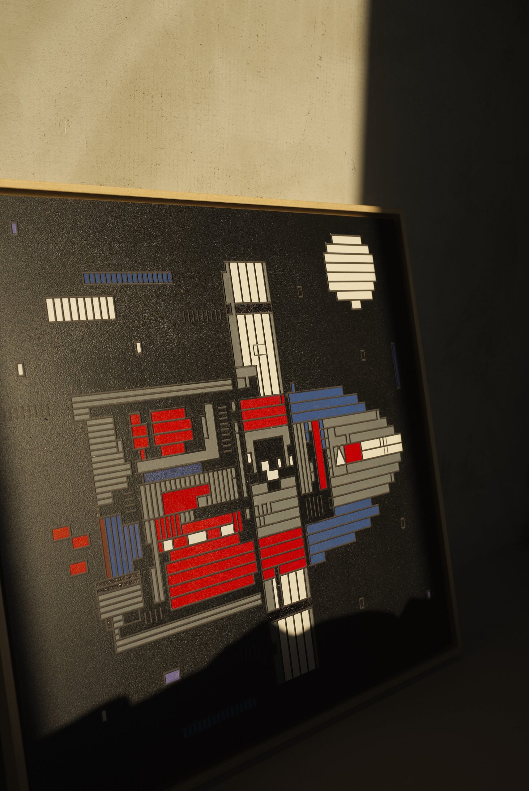 Zolo Kis artwork — framed red and grey rocket artwork leaning against a wall in sunlight