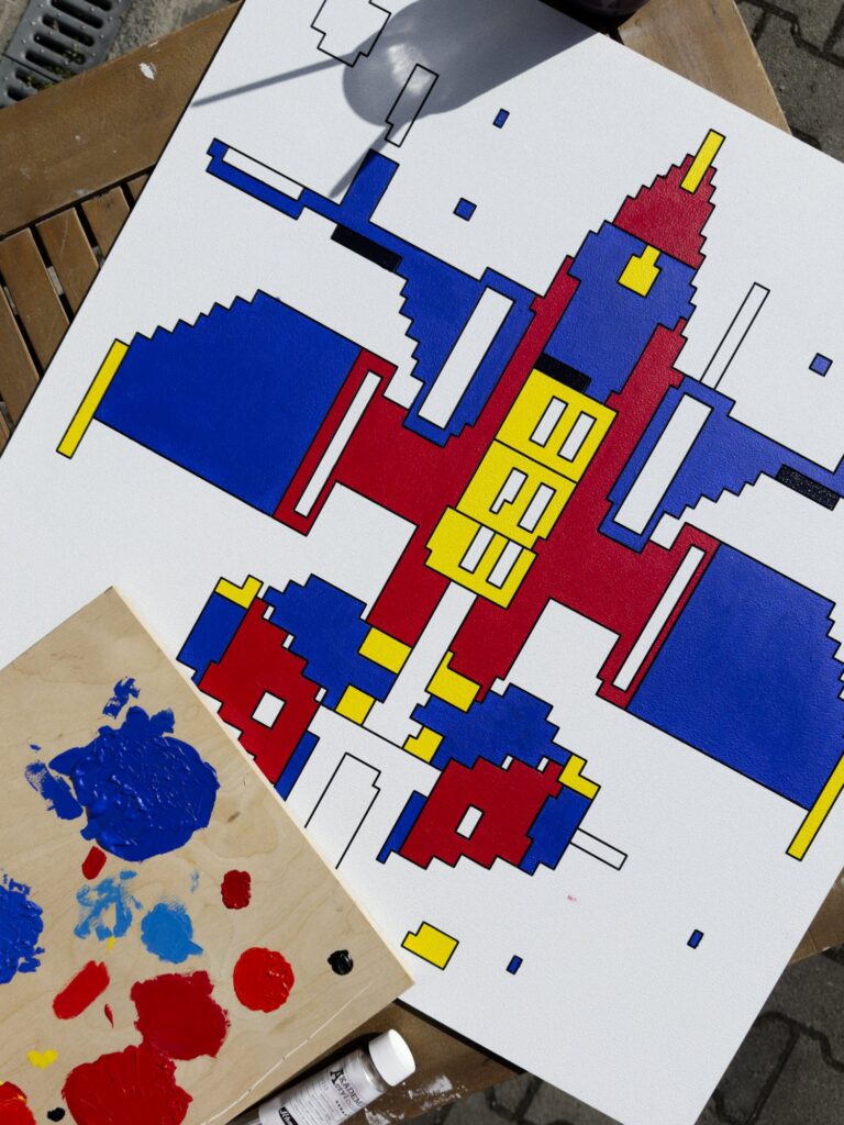 Zolo Kis artwork — blue, red and yellow spacecraft panel during painting on a studio worktable