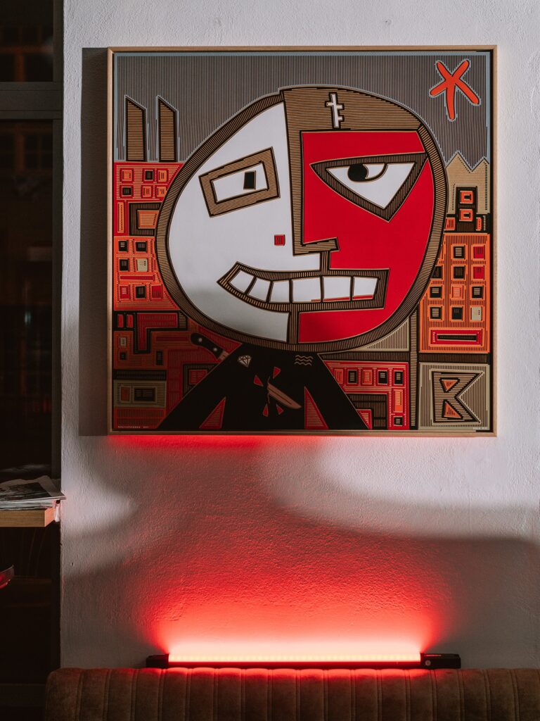 Backstabbed Boy by Zolo Kis — the framed portrait hanging above a radiator illuminated with red light