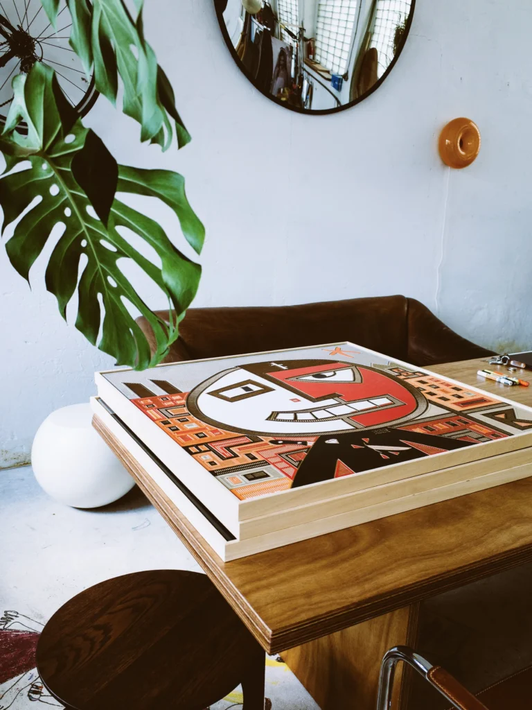Backstabbed Boy by Zolo Kis — the complete framed artwork lying on a wooden table beneath a plant