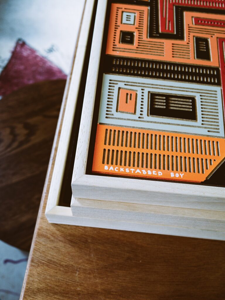 Backstabbed Boy by Zolo Kis — detail of orange, black and pale rectangular patterns beside the wooden frame