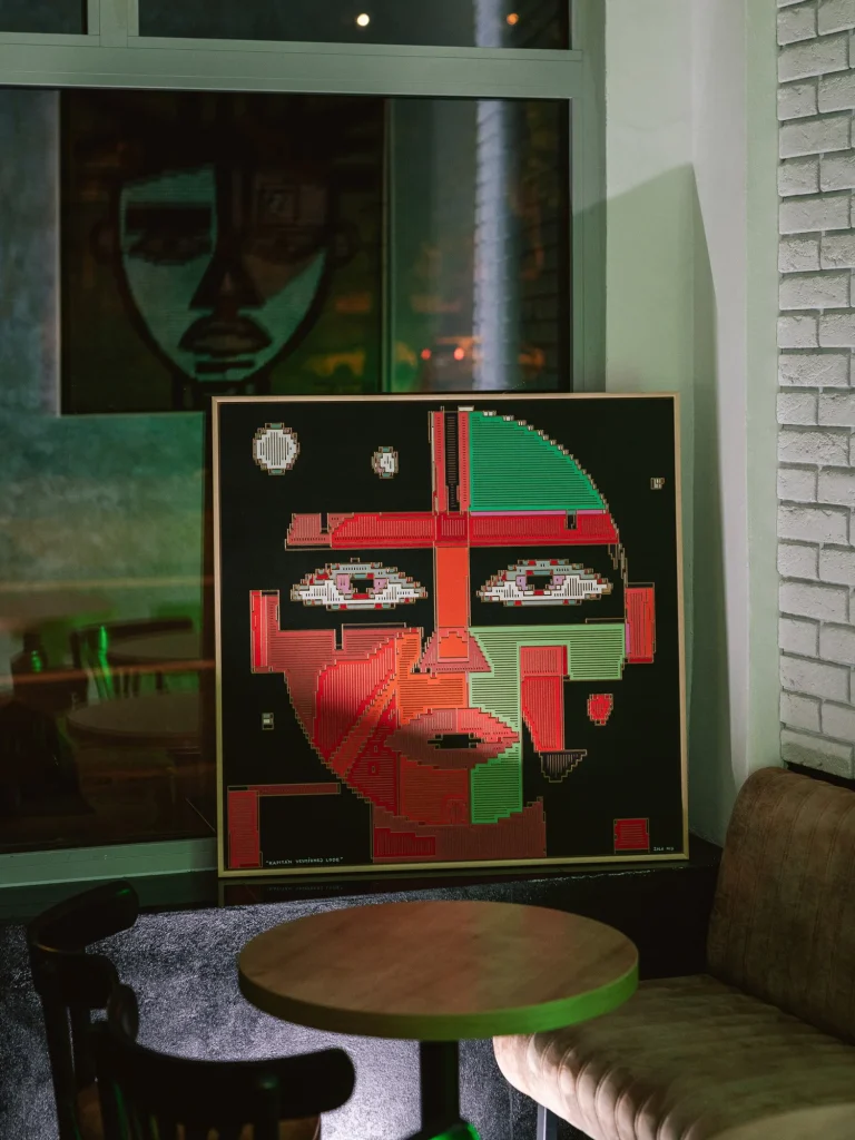 The Captain of the Spaceship by Zolo Kis — the framed red and green portrait displayed beside a window and chair