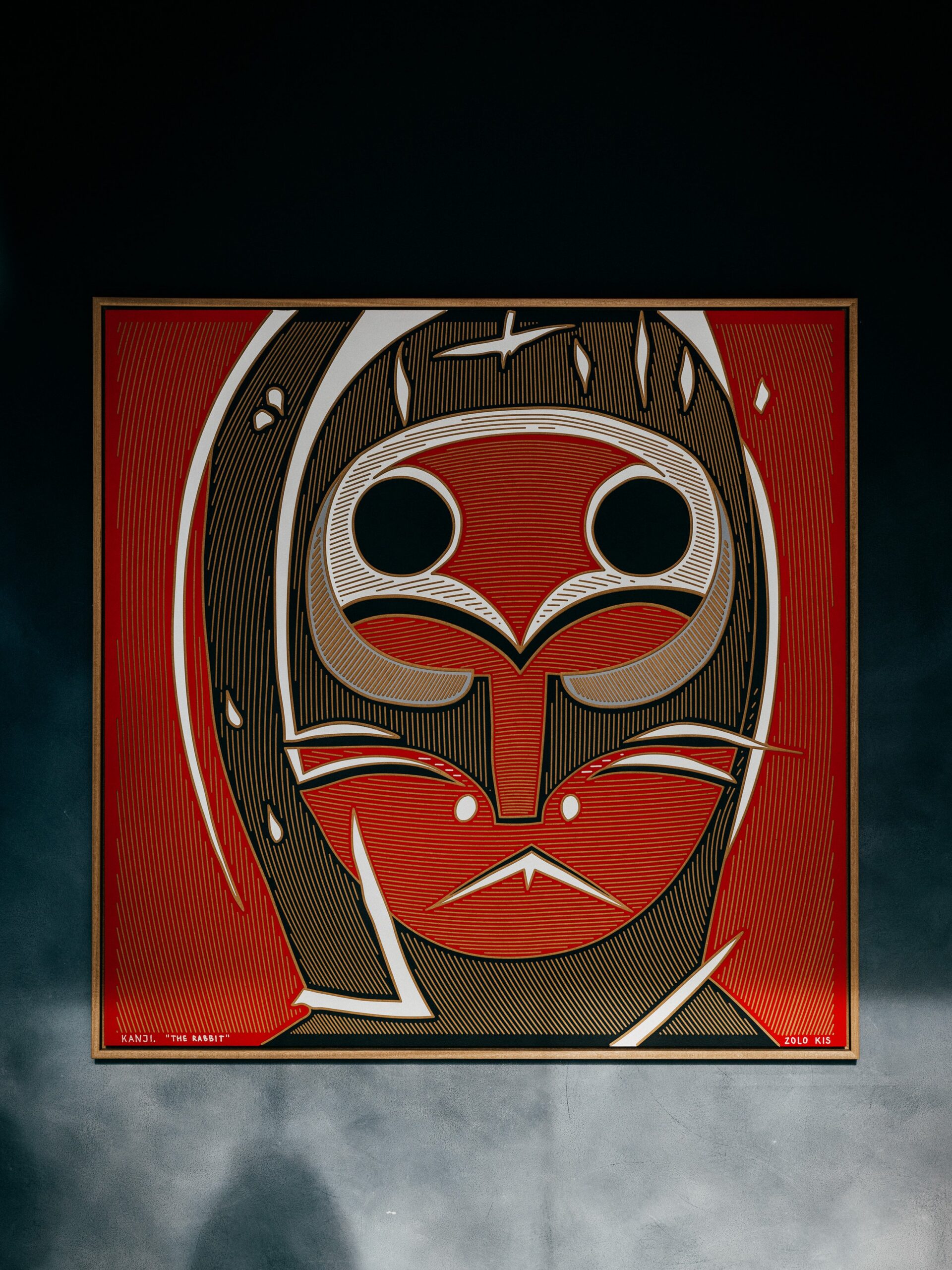 Kanji by Zolo Kis — framed red masked face with black round eyes and pale outlines against a red background